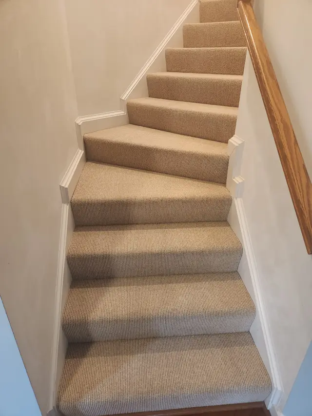Carpeted staircase with a freshly groomed striped nap beside an oak handrail