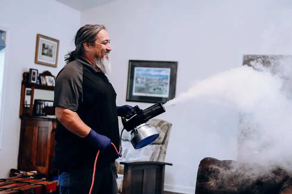 Spectrum technician running a thermal fogging machine in a living room