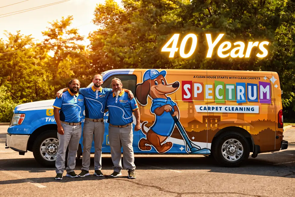 Three Spectrum technicians standing beside the company van wrapped with the dachshund mascot
